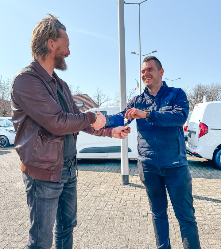 Twee personen die elkaar de hand schudden tijdens de sleuteloverdracht van een voertuig bij Greven Automotive.