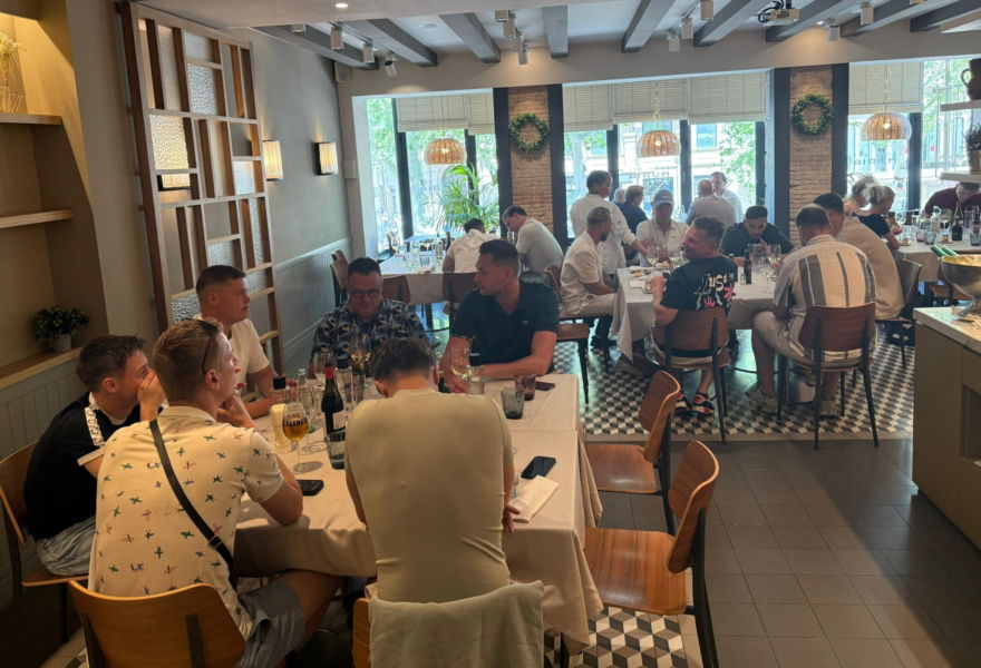 Collega’s zitten samen aan een lange tafel in een restaurant in Barcelona tijdens een gezamenlijk diner.