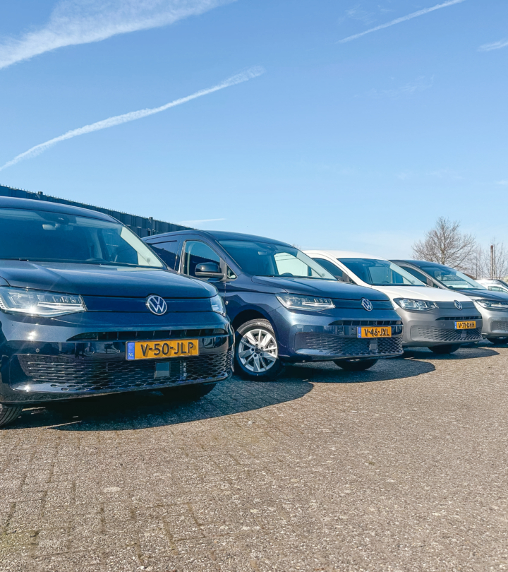 Rij Volkswagen bedrijfswagens in verschillende kleuren die naast elkaar geparkeerd staan op het terrein van Greven Automotive